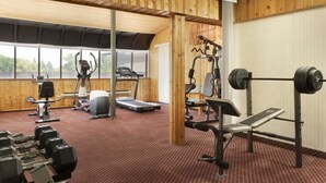 Un gimnasio con diversos equipos de ejercicio, incluyendo cintas de correr, máquinas de pesas y pesas libres.