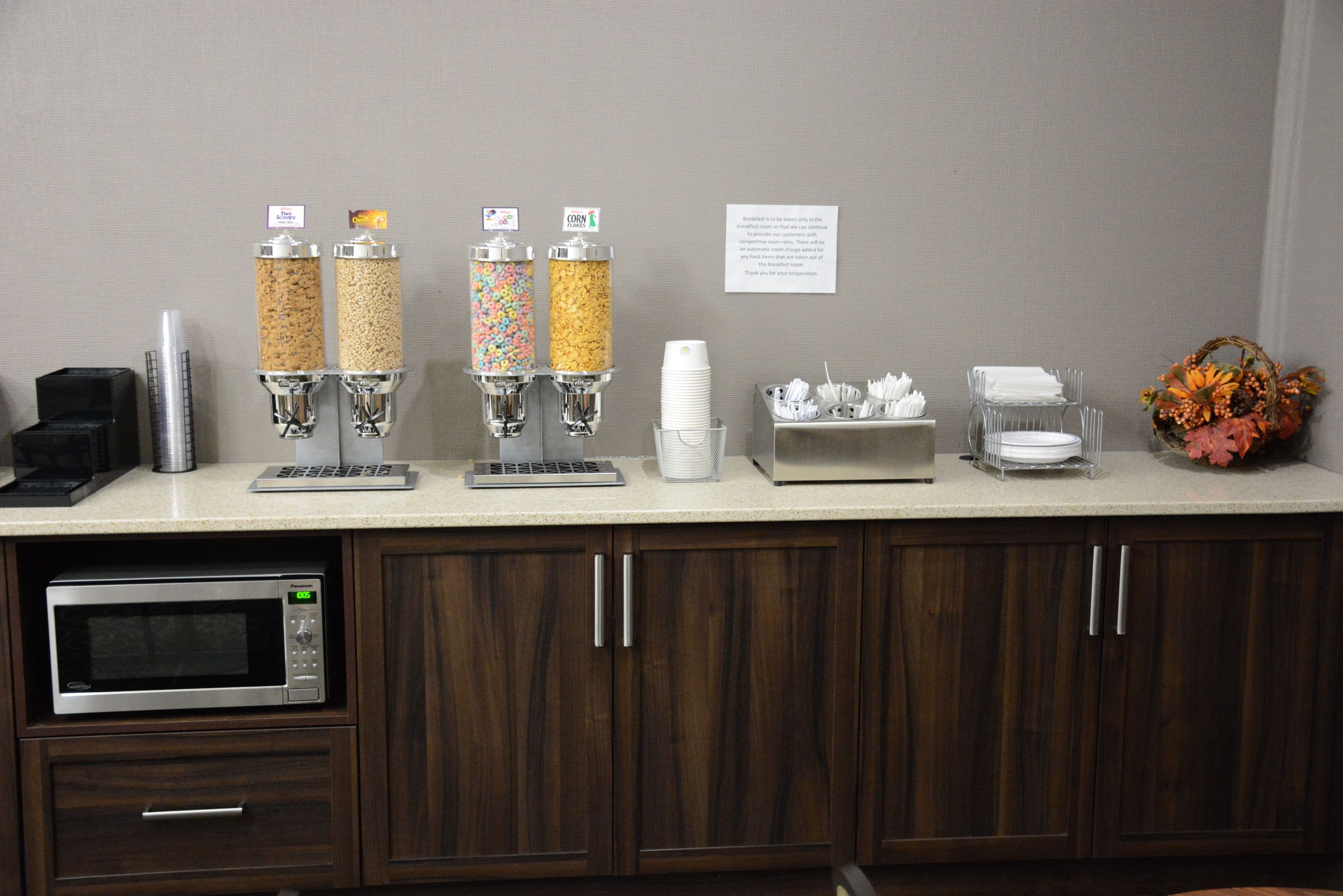 A kitchen counter with a coffee machine, cereal dispensers, and a microwave.