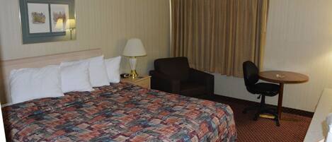 Une chambre d’hôtel avec un grand lit, un bureau, une chaise et une lampe.