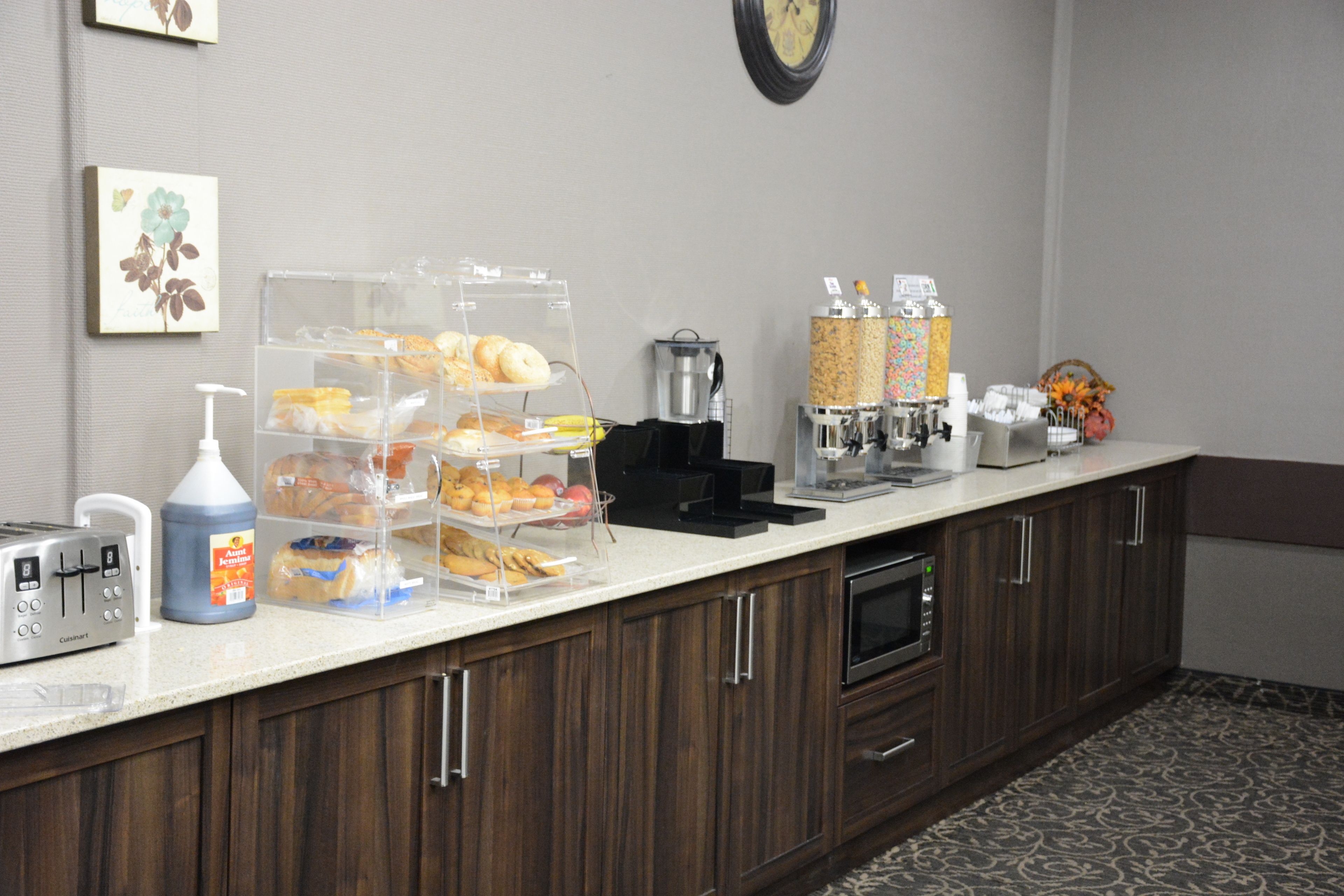 Una barra de desayuno con diferentes alimentos, una máquina de café y un reloj en la pared.