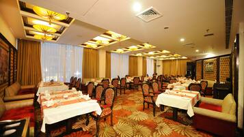 Un salón de banquetes con varias mesas dispuestas para comer, organizadas en filas con sillas.