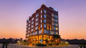 Un hotel de varios pisos con un diseño arquitectónico moderno, que presenta una entrada destacada con un área cubierta y un letrero que indica que es un hotel Marriott.