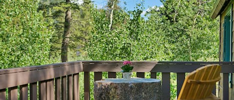 En træterrasse med en træstol og et lille bord med en blomst.