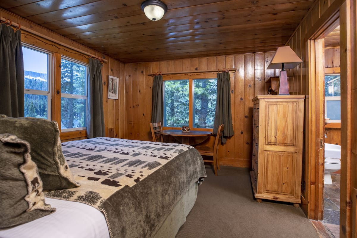 Ein Schlafzimmer einer Holzhütte mit einem Bett, einem kleinen Tisch und einem Schrank.
