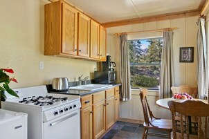 Una cocina con armarios de madera, estufa, fregadero y una ventana con cortinas.