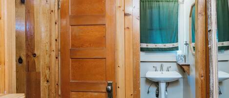 Un interior de madera con una puerta, un lavabo y un espejo.