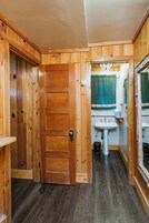 Een houten interieur met een deur, een wastafel en een spiegel.