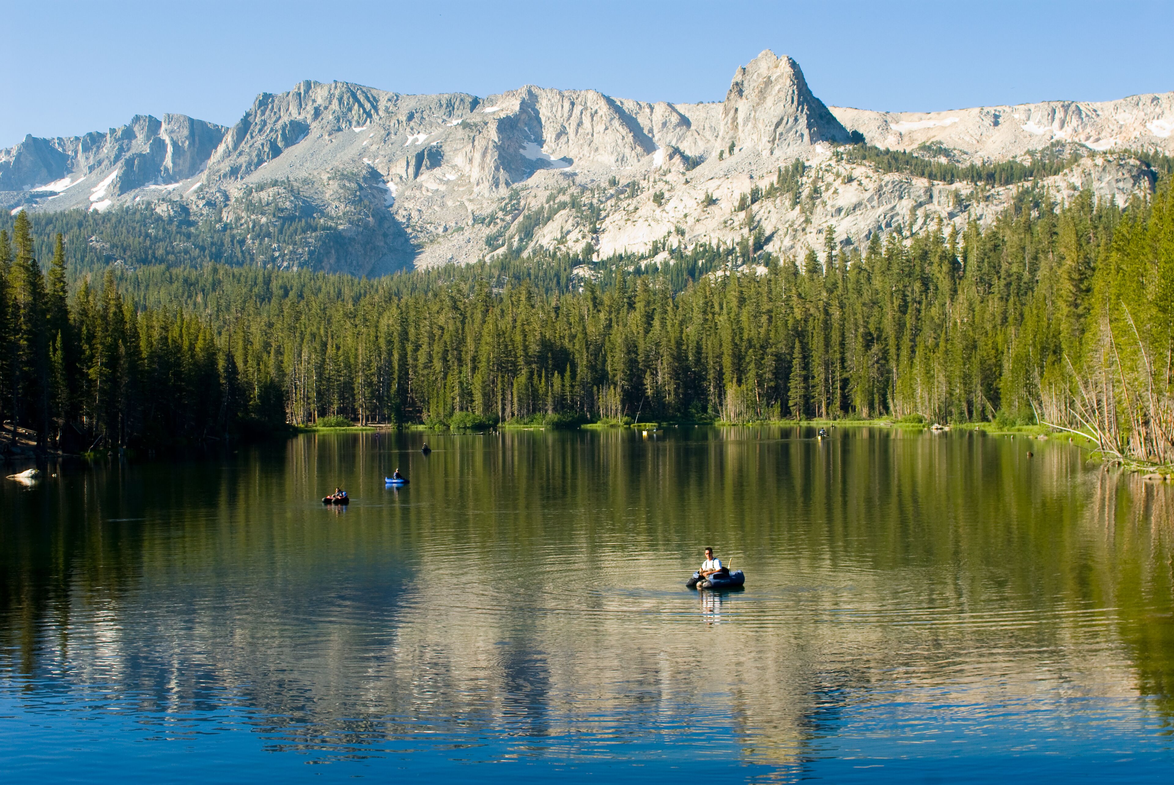 Un lago tranquilo con una cadena montañosa al fondo.