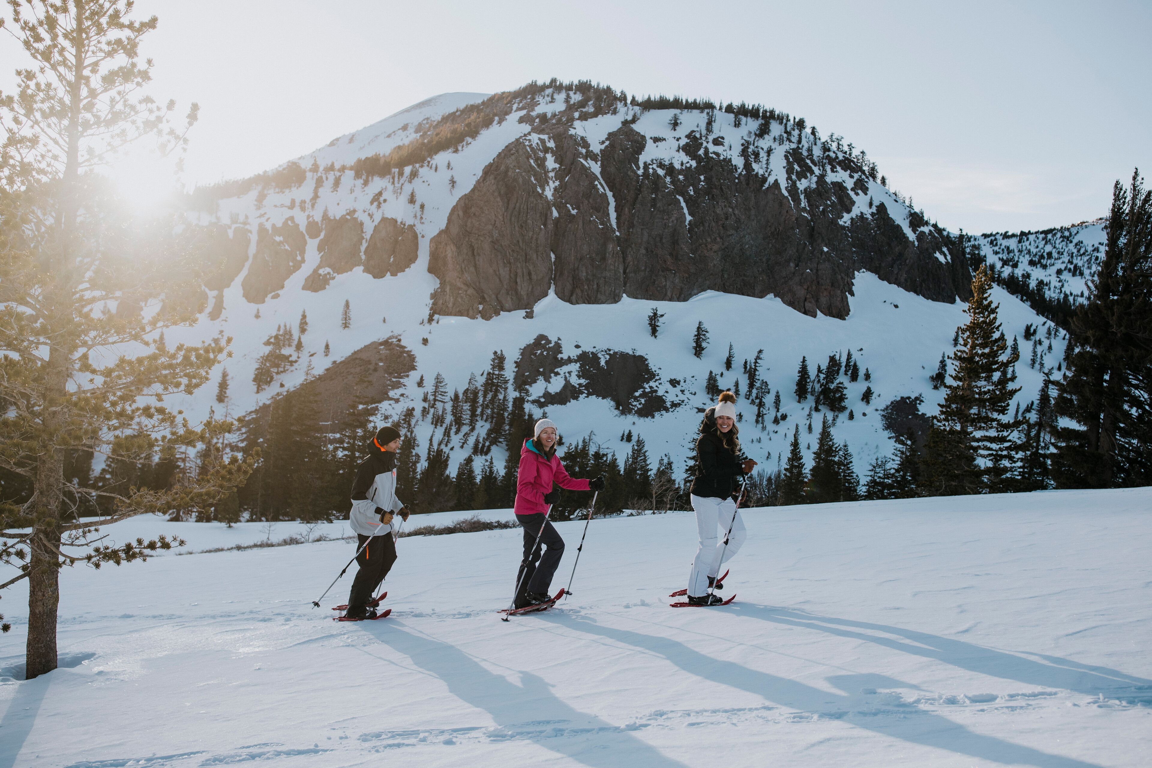 Trois skieurs sur une pente enneigée, avec une montagne en arrière-plan.