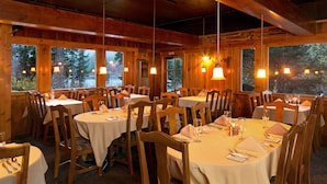 A restaurant with round tables, wooden chairs, and hanging pendant lights. - Tamarack Lodge and Resort (Mammoth Lakes)
