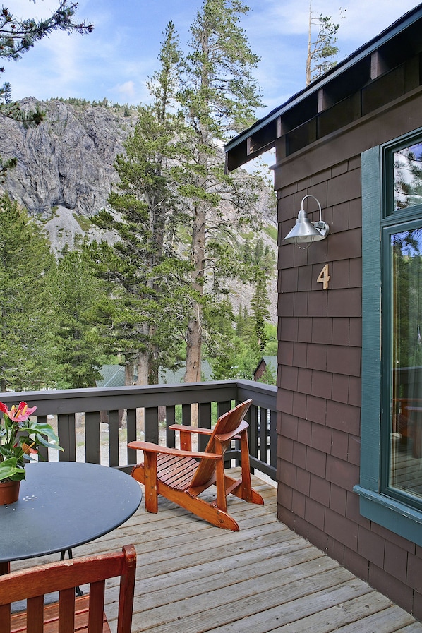 A wooden deck with a table and chairs, a mountain backdrop, and a house number 4.