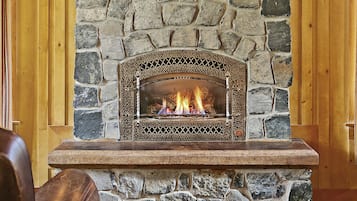 Una chimenea de piedra con fuego, flanqueada por alzas de madera y dos lámparas de pared.