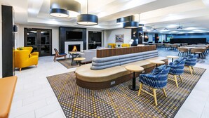 A modern lounge area with a sofa, chairs, and a fireplace. - Holiday Inn Hotel & Suites Tulsa South by IHG (Tulsa)