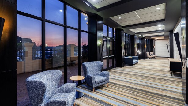 A modern hotel lobby with large windows, seating areas, and a patterned carpet. - Holiday Inn Hotel & Suites Tulsa South by IHG (Tulsa)