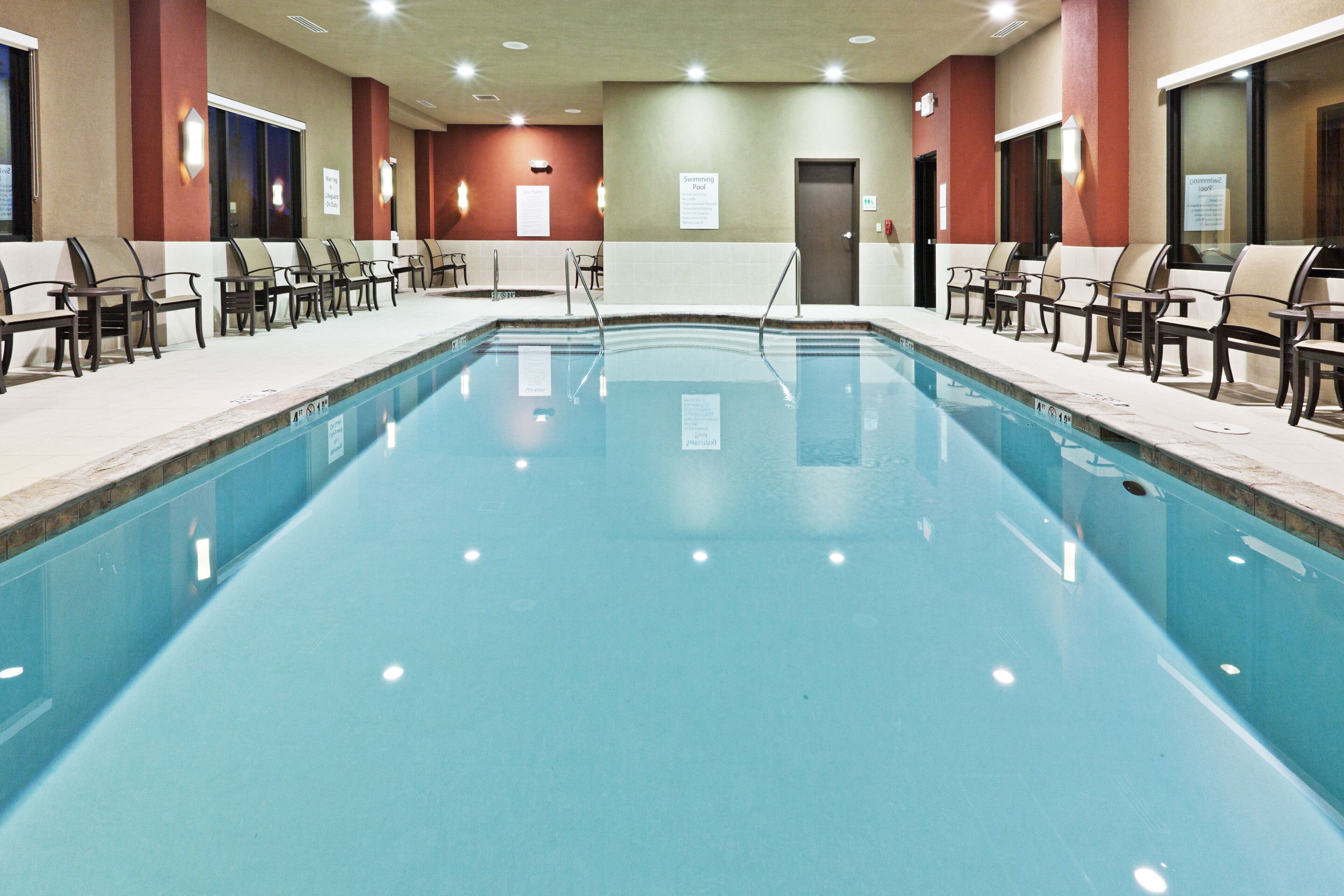 A swimming pool with chairs and a door leading to the spa area.