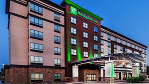 A Holiday Inn & Suites building with a modern design, featuring a prominent green and red color scheme, multiple floors, and a covered entrance area. - Holiday Inn Hotel & Suites Tulsa South by IHG (Tulsa)