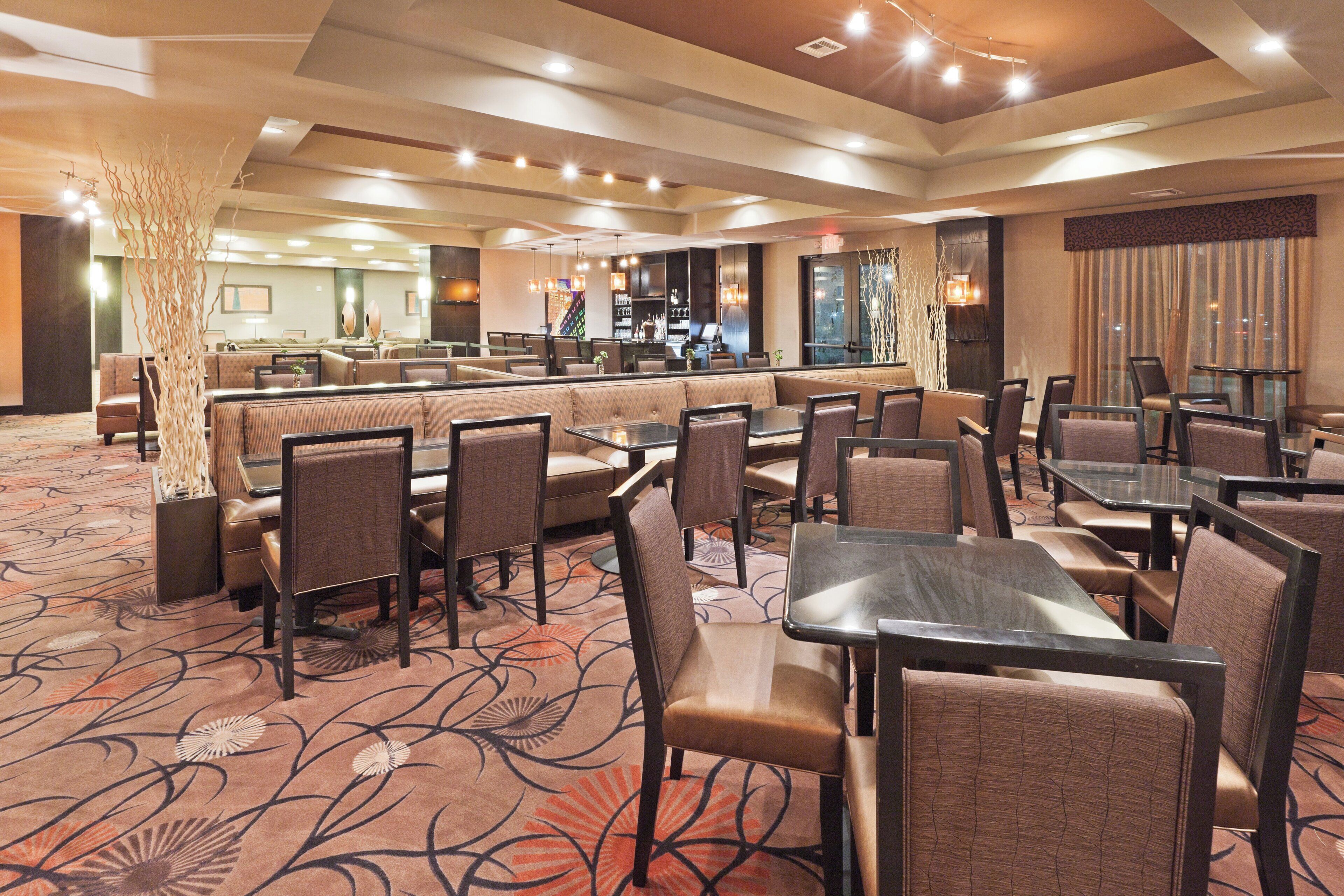 A hotel dining area with booths and tables, a bar, and a patterned carpet.