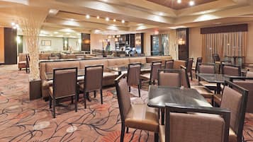 A hotel dining area with booths and tables, a bar, and a patterned carpet.