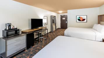 A hotel room with a bed, a desk with a computer, a microwave, and a coffee maker.