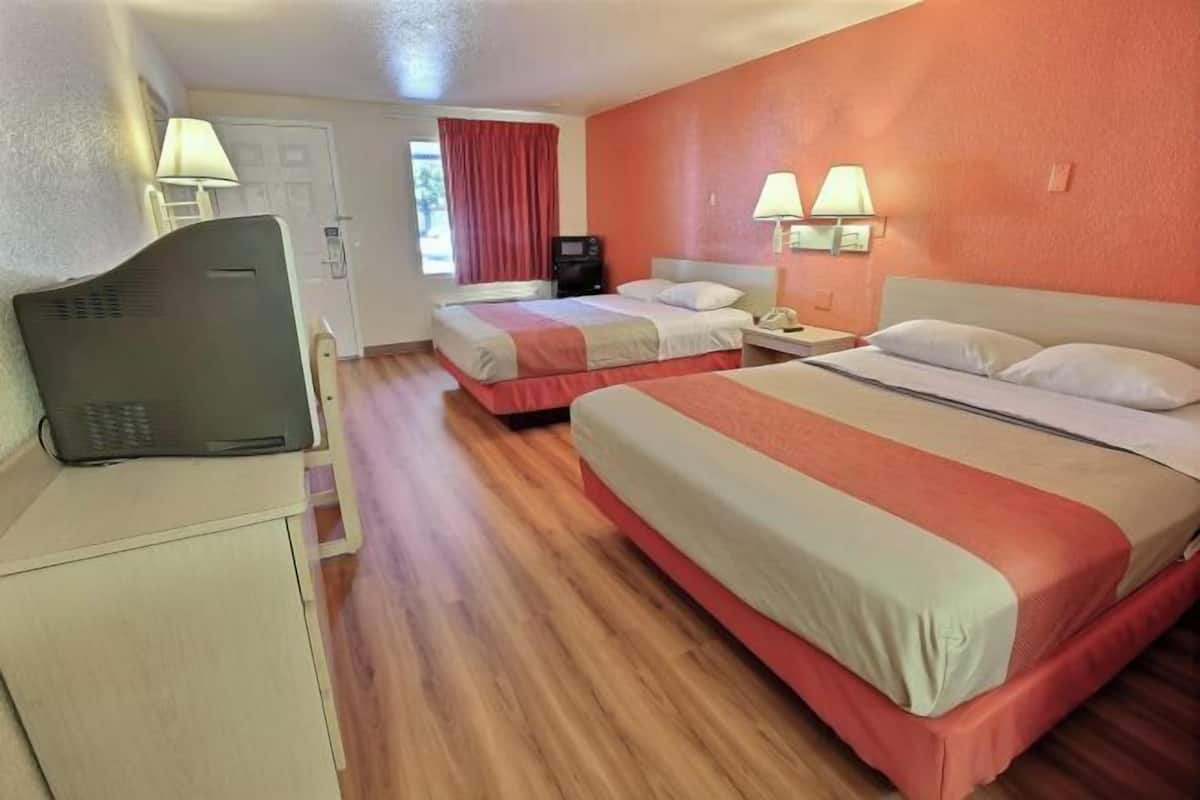 Una habitación de hotel con dos camas, un escritorio con computadora y televisión.
