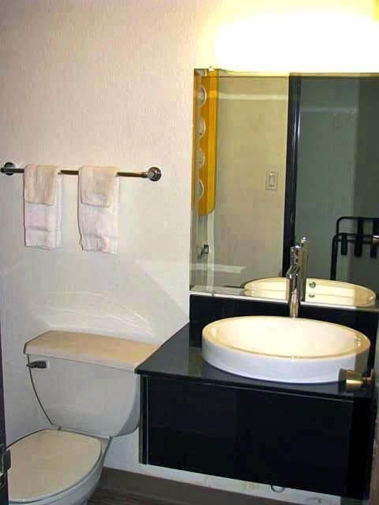 Un baño pequeño con inodoro, lavamanos y espejo.