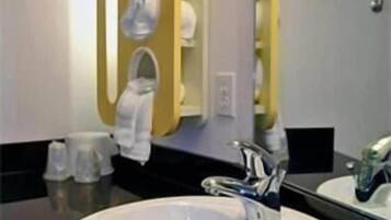 A bathroom with a round white sink, a mirror, and a towel rack.