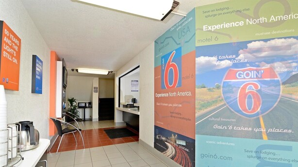 Un espace d’accueil d’hôtel comprenant un comptoir, des chaises et une affiche faisant la promotion des offres « Découvrez l’Amérique du Nord » et « GoIn6.com ».