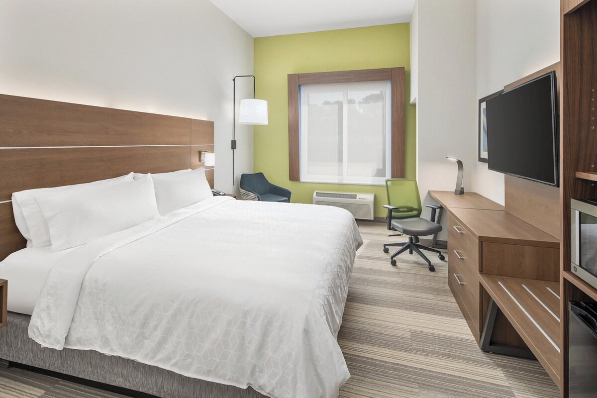 Ein Hotelzimmer mit einem Bett, einem Schreibtisch, einem Stuhl, einem Fernseher und einem Fenster.