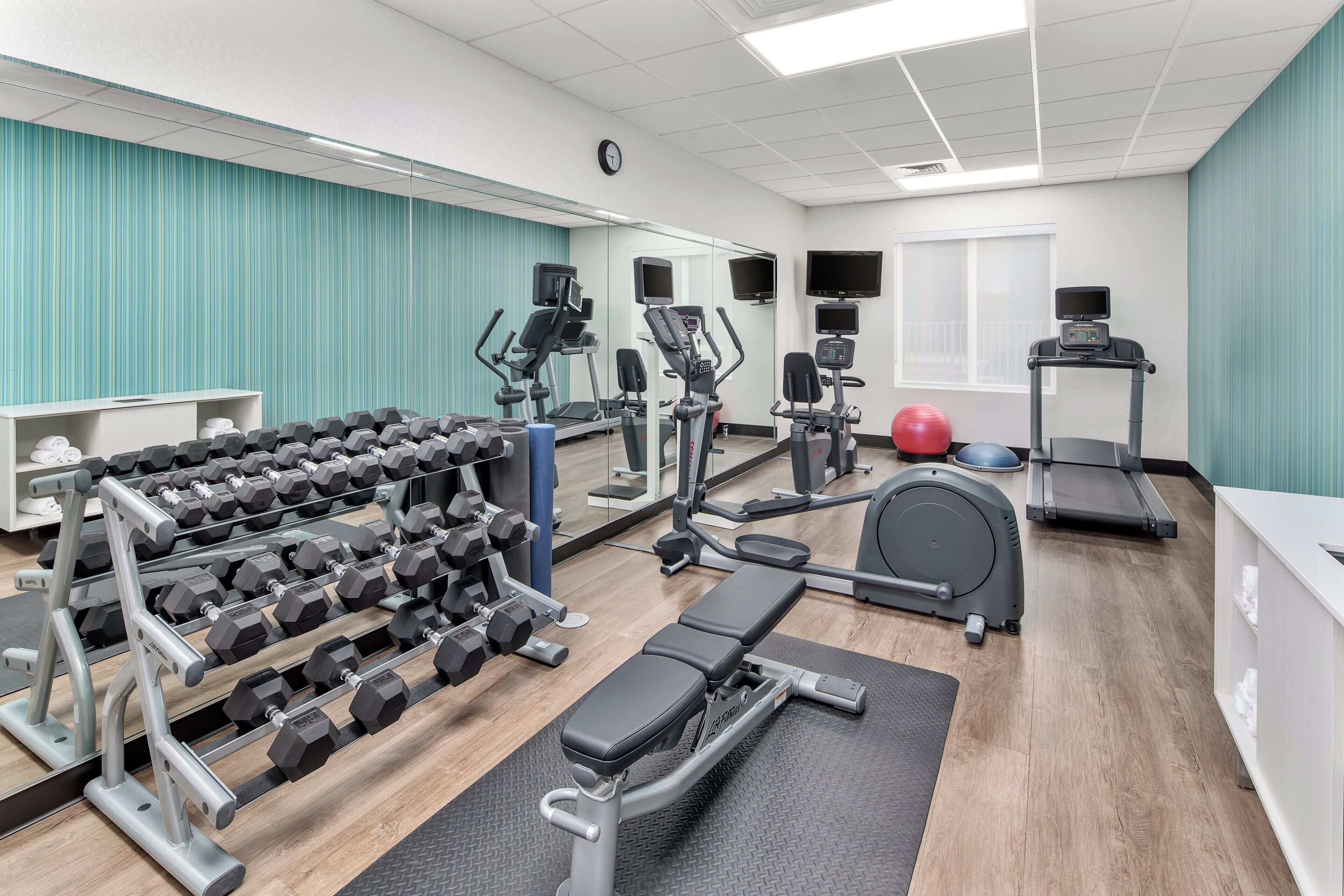Una palestra con diverse attrezzature per esercizi, tra cui manubri, tapis roulant e cyclette.