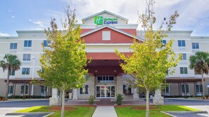 A Holiday Inn Express hotel with a red entrance, stone facade, and a parking lot. - Holiday Inn Express & Suites Palm Bay by IHG (Palm Bay)