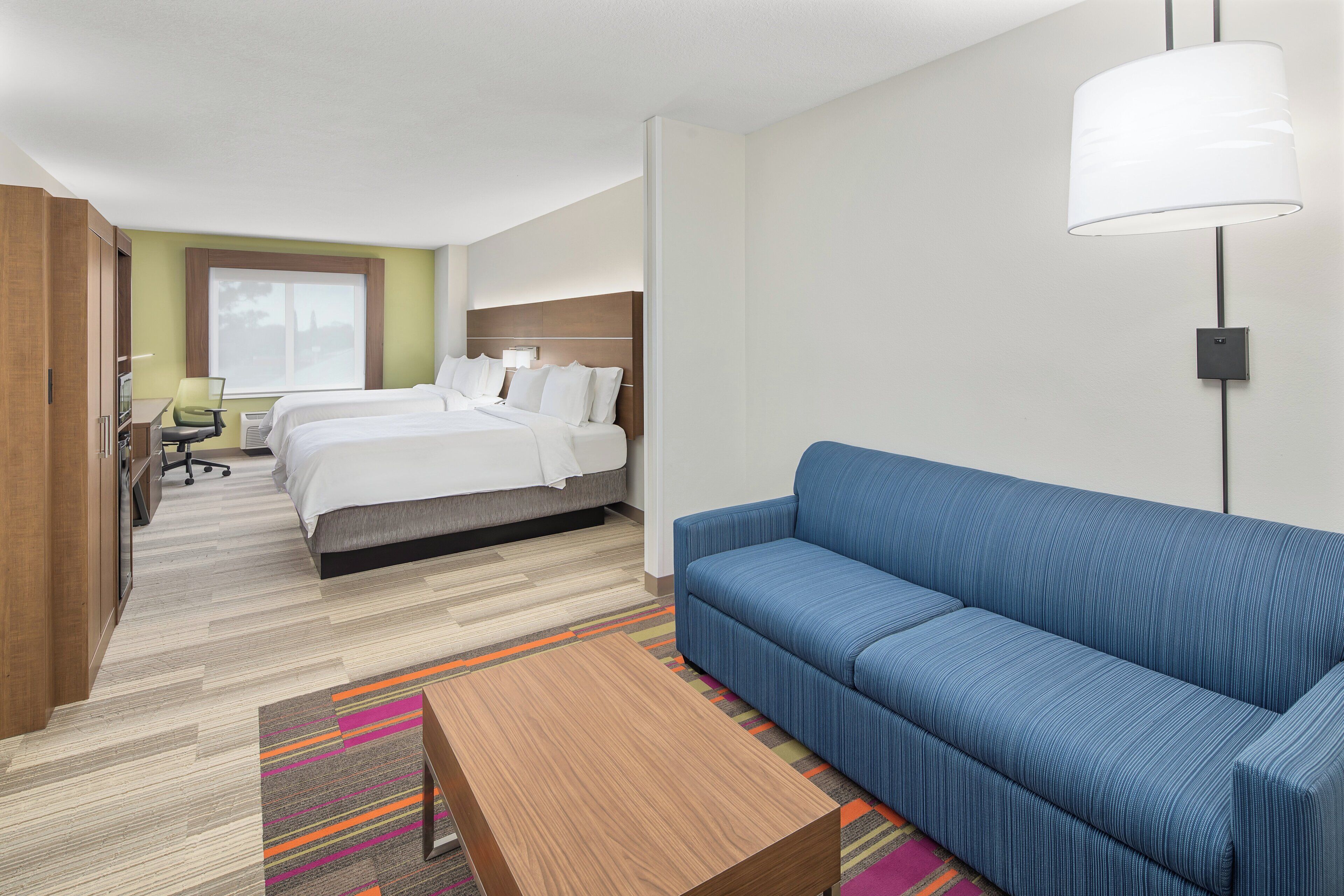 A hotel room with a bed, a sofa, a desk, and a chair.