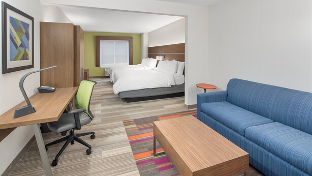 A hotel room with a desk, office chair, sofa, and a bed. - Holiday Inn Express & Suites Palm Bay by IHG (Palm Bay)