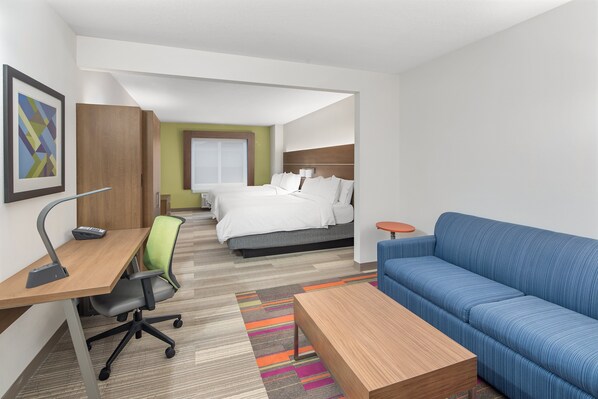 Ein Hotelzimmer mit Schreibtisch, Bürostuhl, Sofa und Bett.