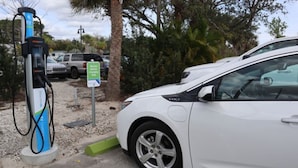 A white car parked at an electric vehicle charging station with a sign indicating it is for electric vehicles only. - Holiday Inn Express & Suites Palm Bay by IHG (Palm Bay)