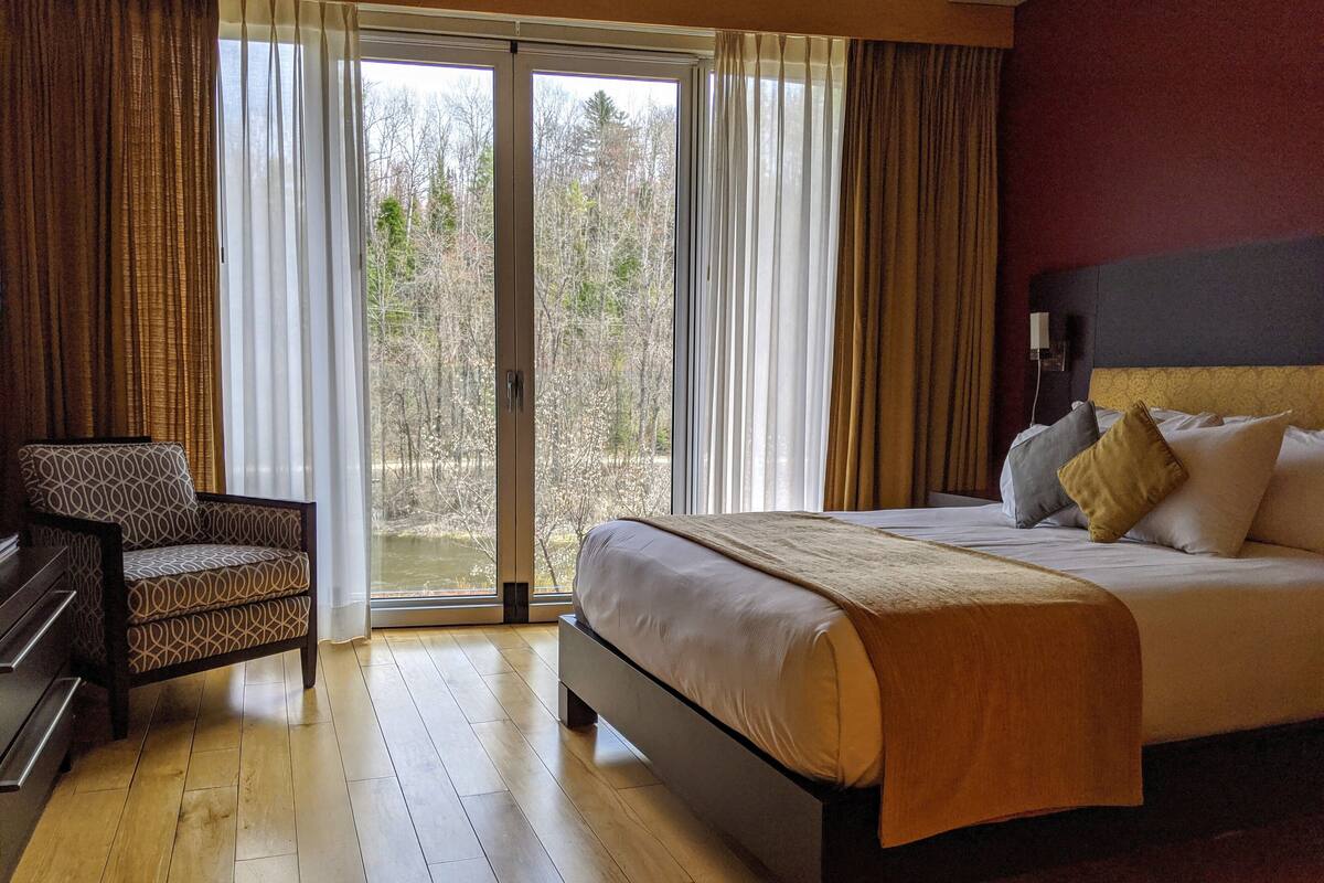 Una habitación de hotel con una cama, una silla y vistas a través de un ventanal.