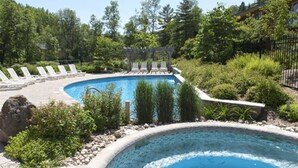 A swimming pool with lounge chairs and a pergola, surrounded by greenery.