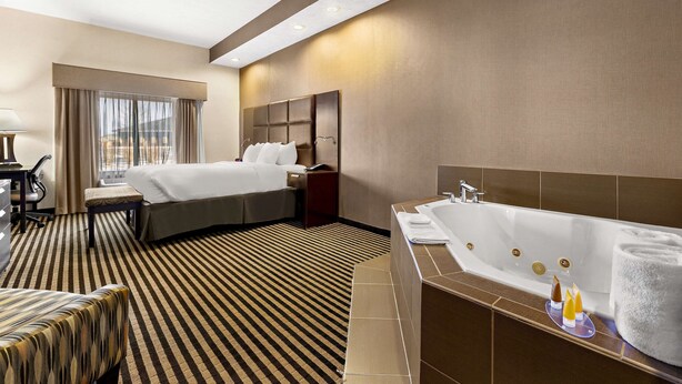 Une chambre d’hôtel dotée d’un grand lit, d’un coin salon séparé, d’une baignoire et d’un bureau avec une chaise.