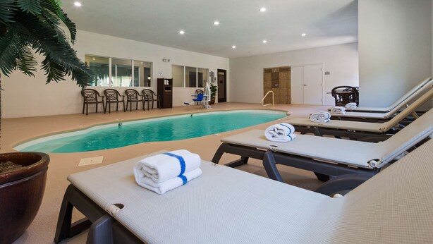 A pool area with lounge chairs, a changing room, and a shower area. - Best Western Oasis Inn (Canadian)