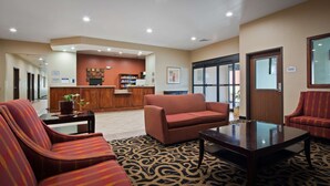 A lobby with a reception desk, a sofa, a coffee table, and patterned carpet. - Best Western Oasis Inn (Canadian)
