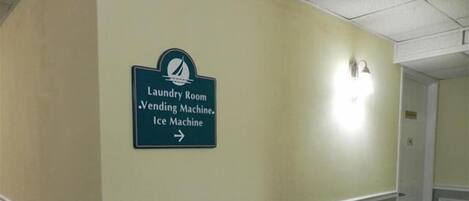 Pasillo con señal que indica el camino a la sala de lavandería, la máquina expendedora y la máquina de hielo.