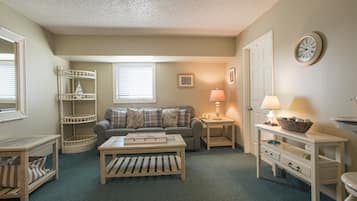 Relax in this cozy living space with a comfortable sofa, wooden coffee table, and shelving unit.