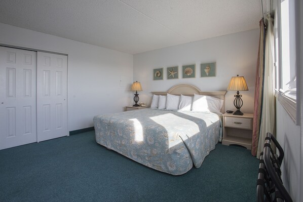 A bedroom with a bed, two bedside tables, a nightstand, a wardrobe, and a window with curtains.