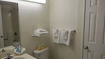 Een kleine, schone badkamer met een wastafel, spiegel, toilet en handdoekhouder.