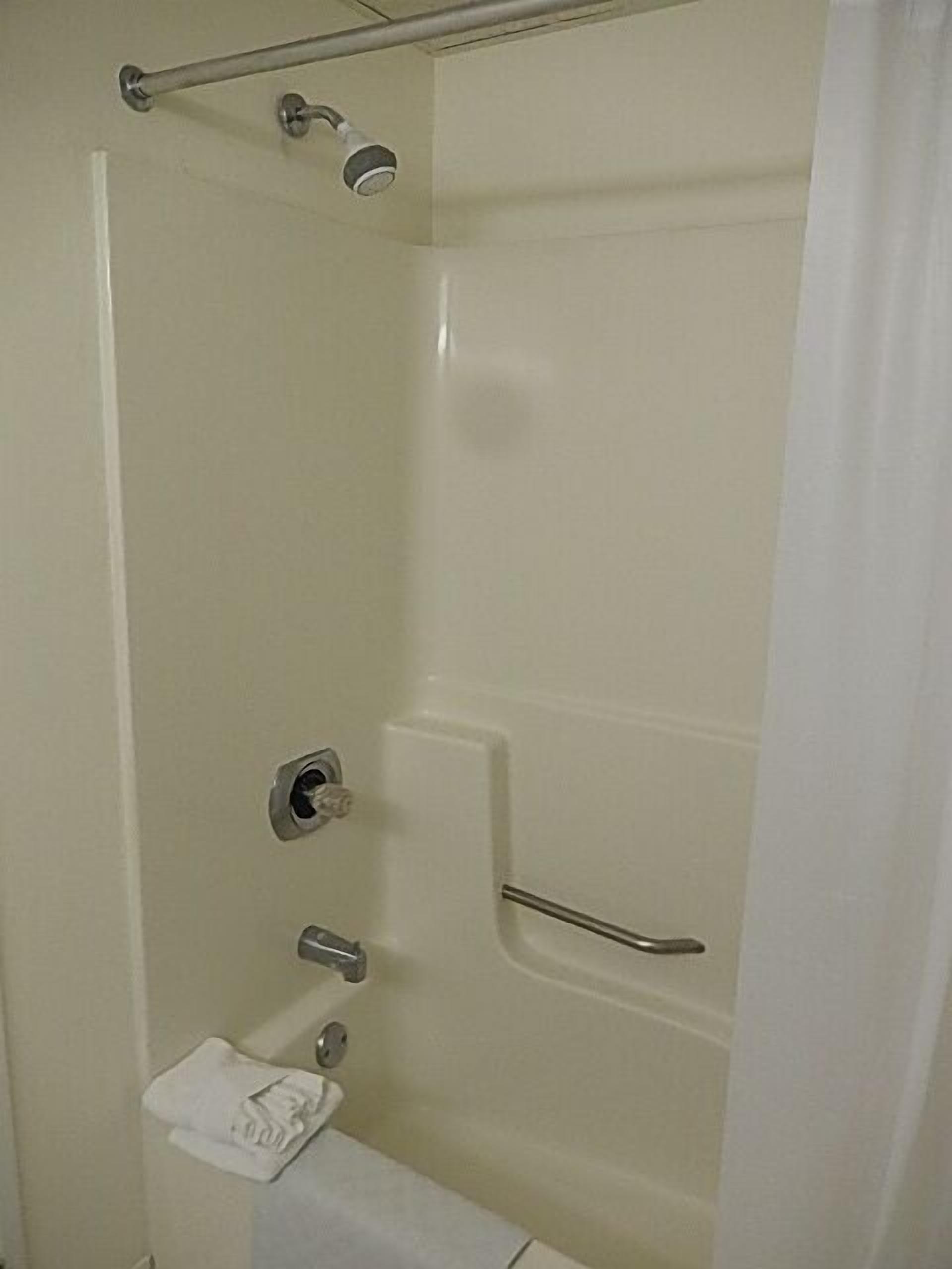 A bathroom with a shower, toilet, and a towel rack.