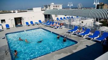 A rooftop pool area with blue lounge chairs and a swimming pool.