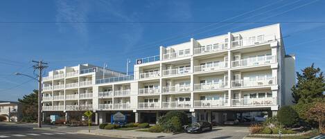 Ein mehrstöckiges Hotel mit Balkonen, einem Parkplatz und blauem Himmel.