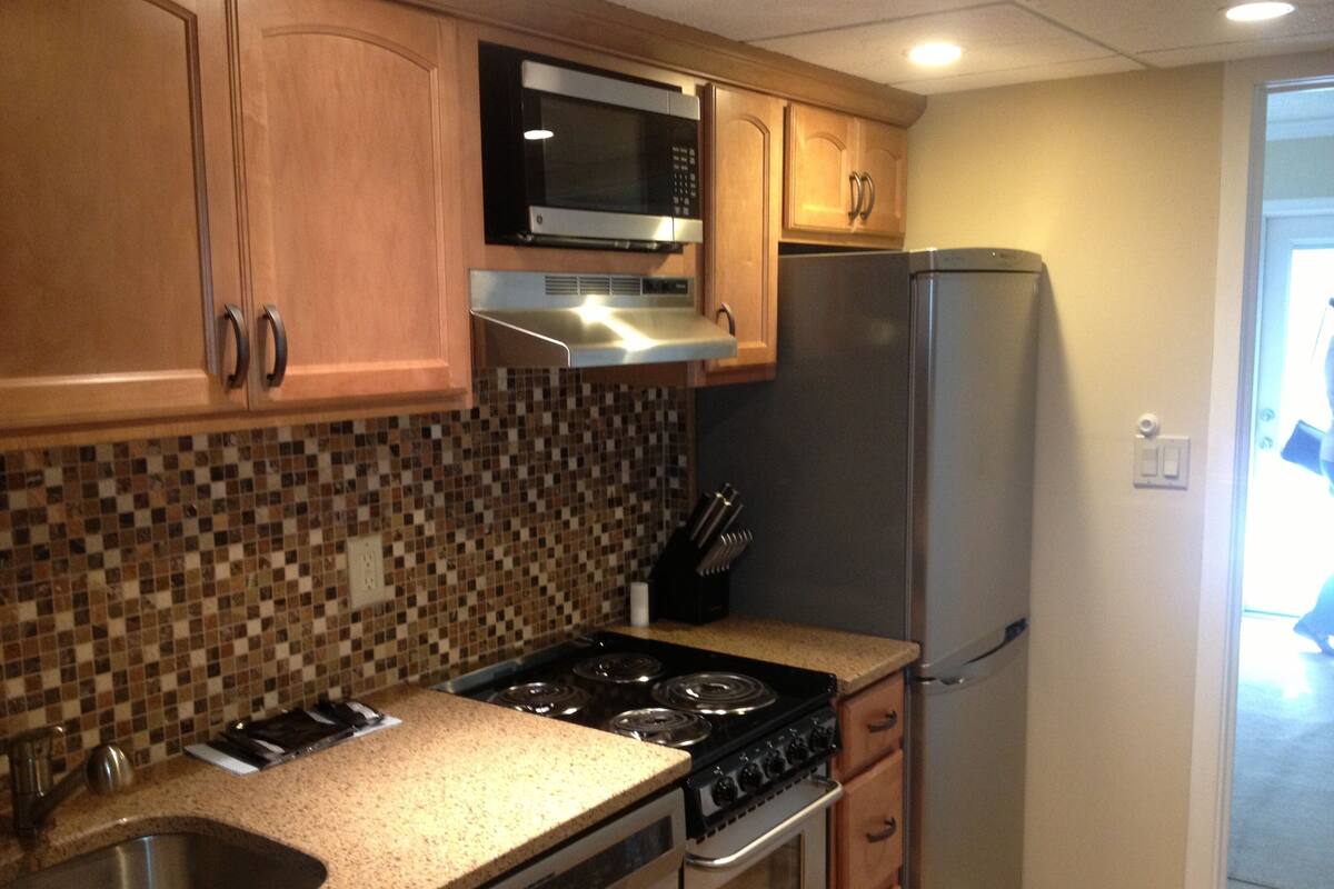 A kitchen with wooden cabinets, a microwave, a stove, and a refrigerator.
