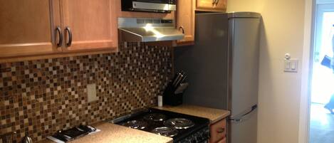 A kitchen with wooden cabinets, a microwave, a stove, and a refrigerator.