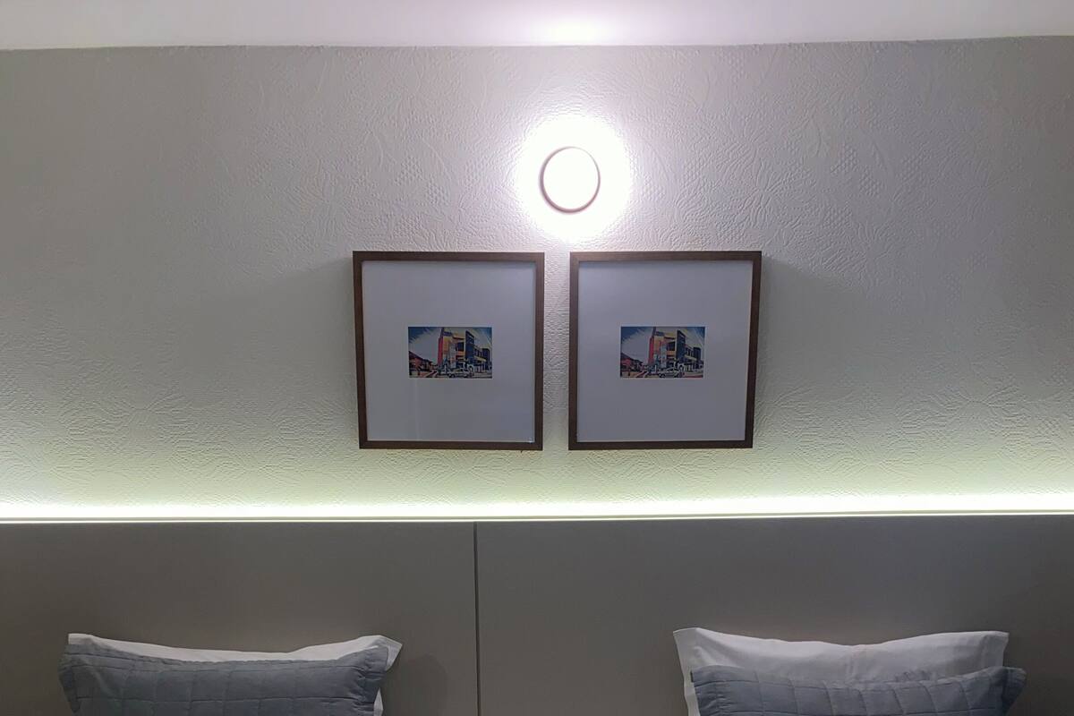 A hotel room with two beds, a nightstand, and a wall-mounted light.