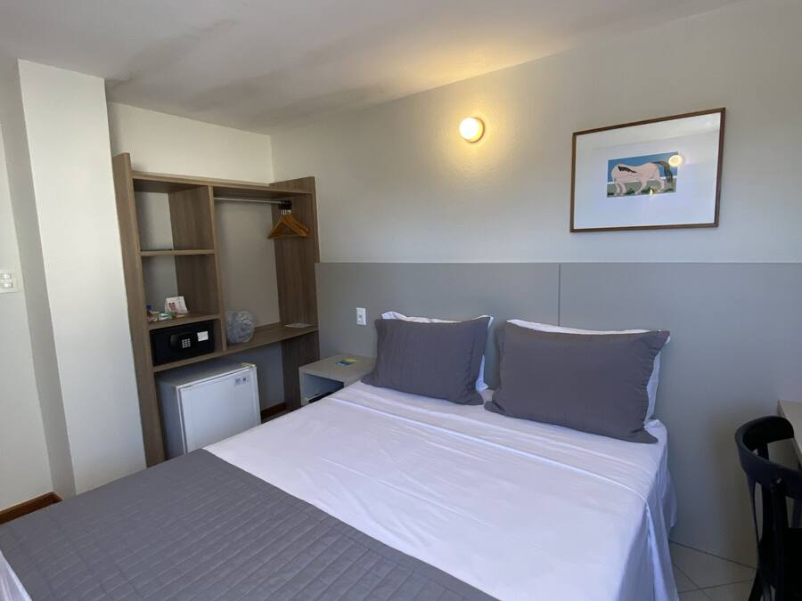 Une chambre d’hôtel équipée d’un lit, d’un bureau, d’une chaise, d’une armoire et d’un petit réfrigérateur.